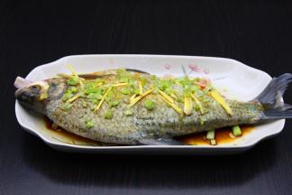 肚内摸上盐、酱油、塞入葱白、生姜丝、香菜根。再淋上油、酱油、盐、料酒、芝麻油、腌制10分钟；