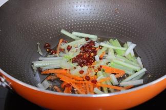 把多余的油倒出，剩一点在锅中，爆炒胡萝卜丝、西芹丝，辣椒；