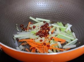 把多余的油倒出，剩一点在锅中，爆炒胡萝卜丝、西芹丝，辣椒；