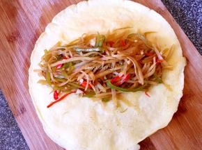 然后将炒好的酸辣土豆丝放入蛋饼的中间