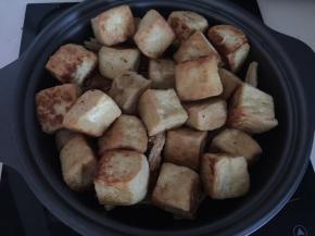 然后将煎好的豆腐放在腐竹上加入适量清水后盖上锅盖大火煮开后转小火焖煮10分钟