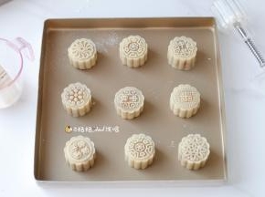 12模具内壁刷上少许面粉，把包好的圆饼胚放入模具里，光滑的一面朝里，收口朝外，用手轻轻按压平整，把模具扣在烤盘上，轻压挤出月饼