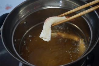 裹好的虾用筷子夹着，放入五成热的油锅中炸熟。