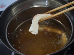 裹好的虾用筷子夹着，放入五成热的油锅中炸熟。