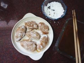 将鸡翅逐一裹上一层淀粉，码入盘内。