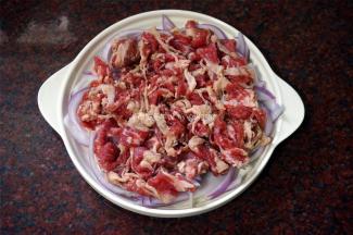 将腌制好的肥肉肉片铺到洋葱上。