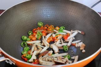 把煎炸过的多余油倒出，留少许在锅中放入红辣椒、青辣椒、香菇爆香；