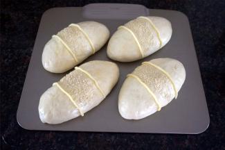 表面刷上全蛋液，中间撒上白芝麻，再用裱花袋里的馅料挤到包子上，如图。放入预热好的烤箱中层，上下火190度烘烤15分钟表面金黄，香气四溢，出炉。