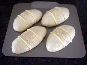 表面刷上全蛋液，中间撒上白芝麻，再用裱花袋里的馅料挤到包子上，如图。放入预热好的烤箱中层，上下火190度烘烤15分钟表面金黄，香气四溢，出炉。