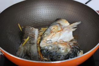 热锅，倒油，把腌制好鱼头鱼尾加一点生姜丝煎至金黄；