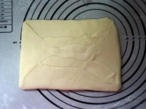 水油皮完全包裹住油酥皮，封口捏紧。自两端分别向三分之一处内折。