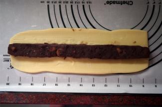 将面团擀成宽度6厘米左右的面片，将馅料放上去，包起来。