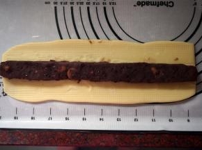 将面团擀成宽度6厘米左右的面片，将馅料放上去，包起来。