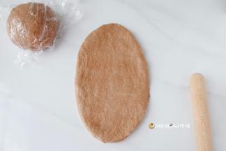 醒发好的面团先用手轻轻拍扁，用擀面杖从中间向上下擀开，擀长椭圆形
