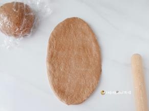 醒发好的面团先用手轻轻拍扁，用擀面杖从中间向上下擀开，擀长椭圆形