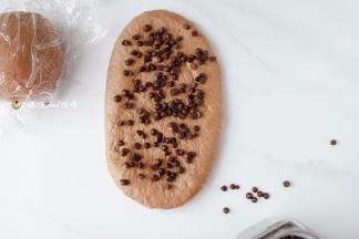 弛10分钟左右，在进行第二次擀卷，把面团擀开，翻面，放上夹馅，我这里放的是巧克力豆，大家也可以根据个人喜好放核桃，杏仁或其他干果蜜饯