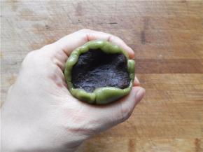 饼皮包住豆沙馅，用虎口慢慢把饼皮往上推（尽量做到让月饼皮均匀覆盖在馅外面。不均匀的地方可适当推补一下，保证完美），收好口。