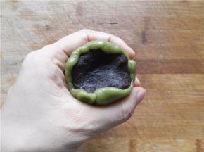 饼皮包住豆沙馅，用虎口慢慢把饼皮往上推（尽量做到让月饼皮均匀覆盖在馅外面。不均匀的地方可适当推补一下，保证完美），收好口。