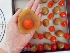 将莲蓉馅压成圆饼状，中间放上咸鸭蛋黄，把它包起来。