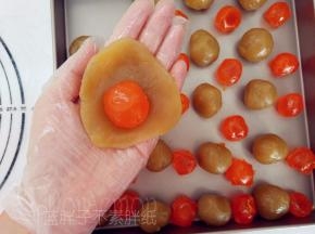 将莲蓉馅压成圆饼状，中间放上咸鸭蛋黄，把它包起来。