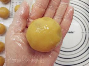 一手大拇指按住馅料，另一手虎口往上推饼皮，使它紧贴着馅料并慢慢地往上爬。最后收口，并将其滚圆。