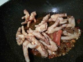 锅里放少许油，加生姜丝，花椒，大料，桂皮，香叶，小茴香，郫县豆瓣酱炒香 ，放入控好水的鸡爪翻炒，