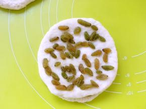 之后再擀第三份面团，再盖在铺好葡萄干的两片圆片上，如此将五分面团全部擀好，一层面片一层葡萄干的铺好