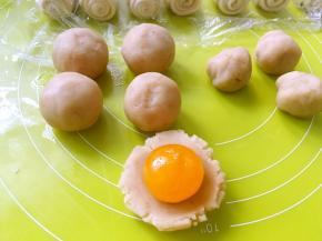 取一块莲蓉馅，用手掌压扁，包裹上咸蛋黄，收好收口