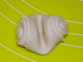 将醒好的面团从中间压一下，然后压扁