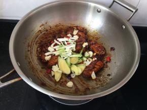 同时加入蒜片，姜片，葱段，小米椒，炒至段生即可