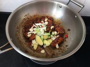 同时加入蒜片，姜片，葱段，小米椒，炒至段生即可