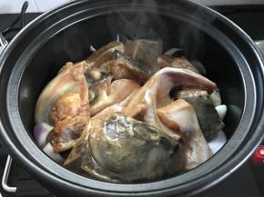 把鱼头放在洋葱上面，多余的腌料汁无需放入。