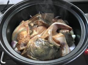 把鱼头放在洋葱上面，多余的腌料汁无需放入。