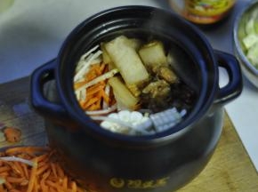 9、将炒过的冬瓜肉，移入陶煲王锅内，然后放入玉米、萝卜丝、香菇等。