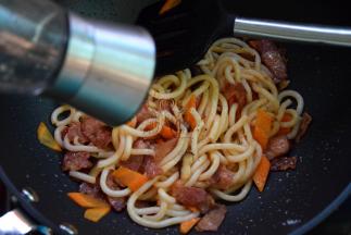 然后加入乌冬面、培根炒匀，磨入黑椒碎