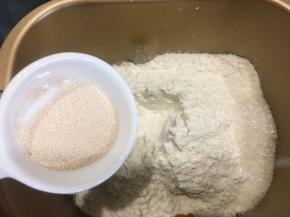 边角倒入白糖，中间挖一个小洞放入耐高糖酵母，用面粉盖住。按揉面模式揉十分钟