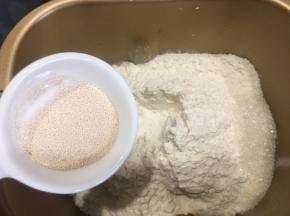 边角倒入白糖，中间挖一个小洞放入耐高糖酵母，用面粉盖住。按揉面模式揉十分钟