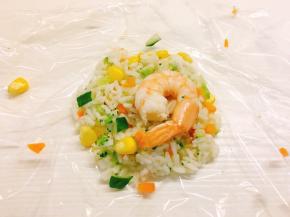 取一张保鲜膜，舀一勺饭，再放一个虾在饭的中间