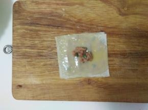 放上第三张馄饨皮，刷上蛋液，中间放上肉馅。
