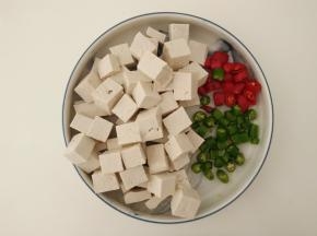 把豆腐切成小方块，青红辣椒切成块。