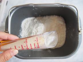 将面粉、奶粉放入面包机桶中，在一侧角落里放入酵母和盐