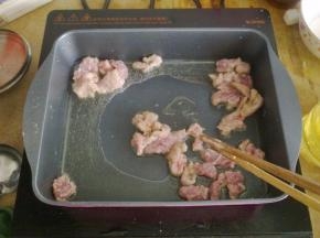 锅里倒入油，把肉放入煎炸至表面金黄。