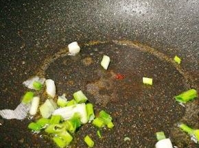 锅中余油加热，爆香葱段，