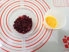 先来制作馅料。蔓越莓切碎，鸡蛋打散，称好所需蛋液。