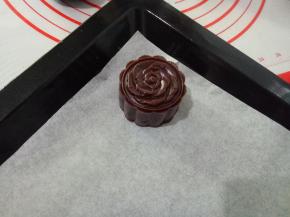 把月饼生坯扣出来，放入垫了油纸的烤盘中。