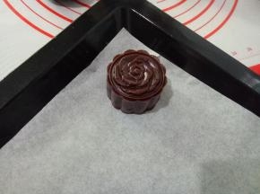 把月饼生坯扣出来，放入垫了油纸的烤盘中。