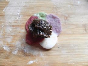 用擀面杖将饼皮擀成中间厚、周围薄，将25克枣泥馅放饼皮中间（桌面撒少粉熟糯米粉）。