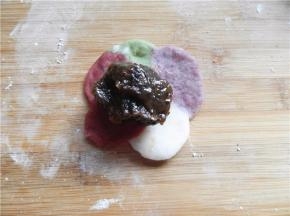 用擀面杖将饼皮擀成中间厚、周围薄，将25克枣泥馅放饼皮中间（桌面撒少粉熟糯米粉）。