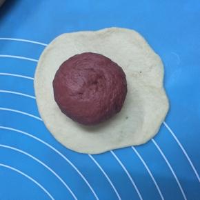 取一白色面团，擀成圆形，将红色面团包住，捏紧收口，揉圆。