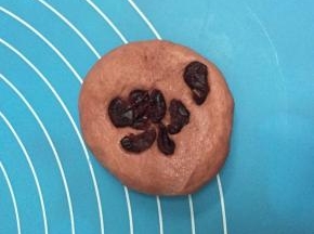 取一红色面团，加入少量蔓越莓，揉圆。